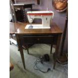 A mid-20th century oak sewing table with a Singer electric sewing machine