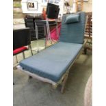 A weathered teak garden lounger with green cushion