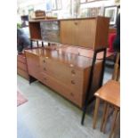 A mid-20th century teak highboard having a glazed top section with pull down flap and the base