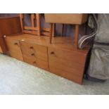 A mid-20th century teak unit having three drawers flanked by cupboard doors