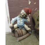 A composite stone garden ornament of a gnome on a barrel45cm tall.