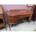 An early 20th century walnut veneered desk having a centre drawer flanked by two drawers on cabriole