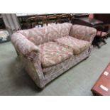 A late Victorian drop arm settee upholstered in a floral cut fabric