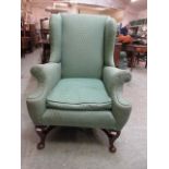 An early 20th century high back wing armchair on cabriole supports