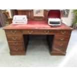 An early 20th century walnut twin pedestal desk with red tooled leather insert to top