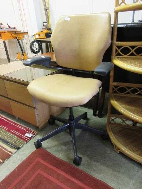 An office chair upholstered in a tan leatherette fabric on five star base