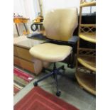 An office chair upholstered in a tan leatherette fabric on five star base