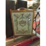 An early 20th century oak framed firescreen with floral needlework panel