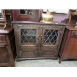 A mid-20th century oak effect glazed cabinet having two cupboard doors to base