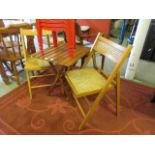 A teak folding garden table along with a pair of folding garden chairs