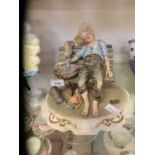 A Capodimonte model of man sat on bench as cats pilfer his catch