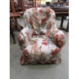 An Edwardian walnut framed tub nursing chair having a loose floral and bird design cover