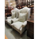 A pair of early 20th century walnut framed high back wing armchairs upholstered in a pale green