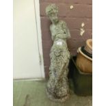A composite stone garden ornament of scantily clad lady
