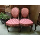 A pair of walnut bedroom chairs upholstered in a patterned red silk fabric