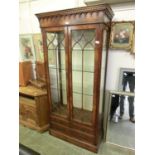 A reproduction mahogany display cabinet with dental cornice over two astragal glazed doors and