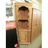 A modern pine floor standing corner cupboard