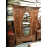 An Edwardian satinwood banded and marquetry wardrobe, the oval bevel mirror plate to door over