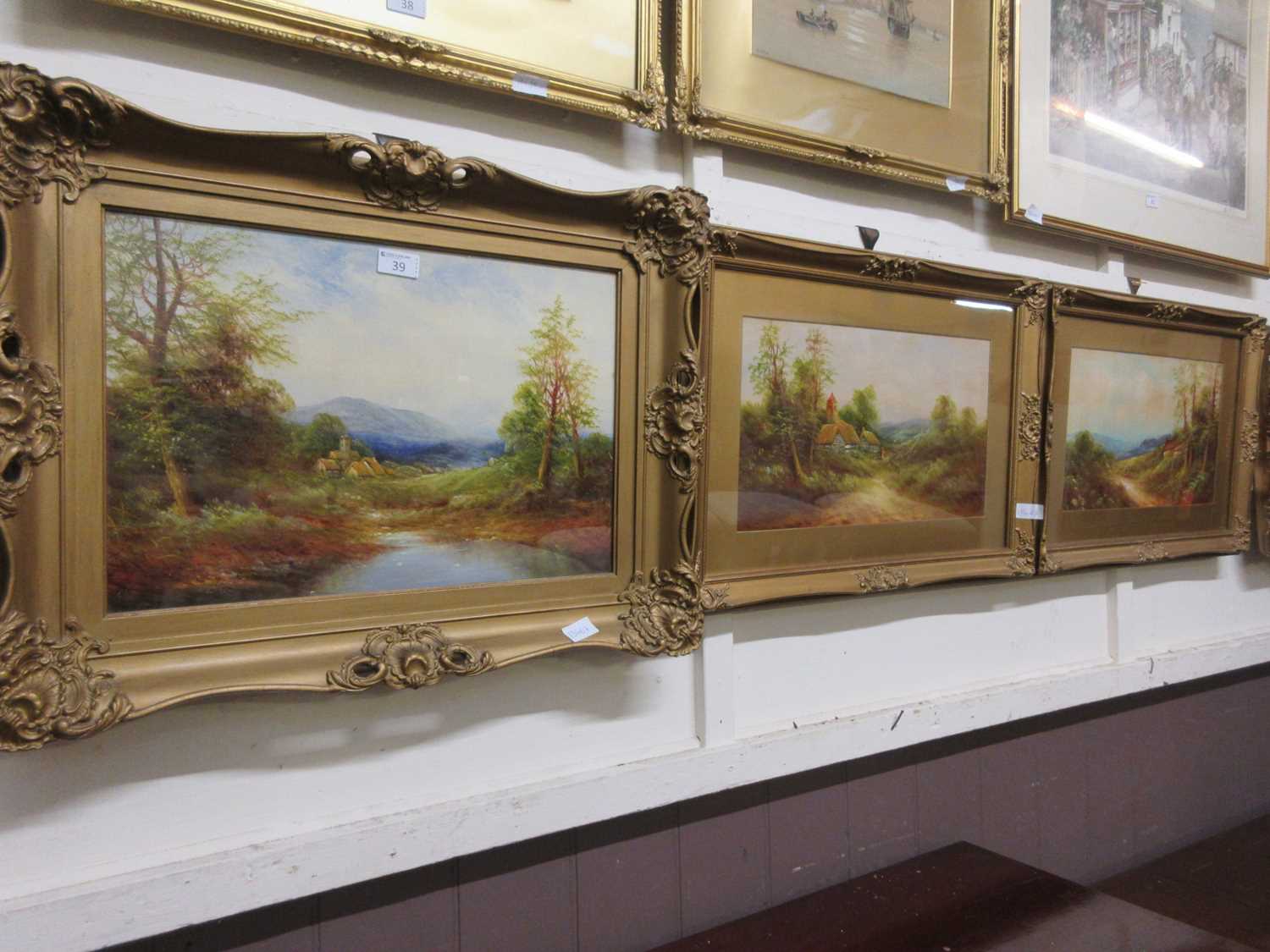 Three framed and glazed oleographs of countryside in gilt frames