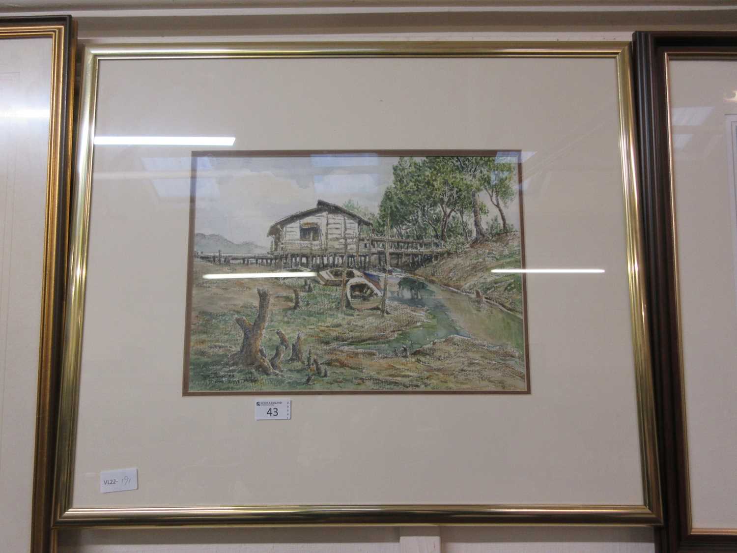 A framed and glazed watercolour of a boat house with rowing boats, signed bottom left