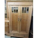 A modern pine cabinet, bevelled glazed cupboard doors over single drawer on turned feet