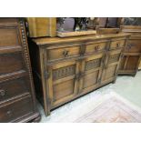 A reproduction oak sideboard, the top over three drawers and three carved panel doors