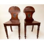 HALL CHAIRS, a pair, Regency mahogany with carved and painted roundel centred backs. (2)