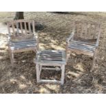 GARDEN ARMCHAIRS AND TABLE, a pair well weathered teak, slatted with arched backs together with a