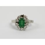 AN EMERALD AND DIAMOND LADIES DRESS RING, white metal, the central emerald stone of approximately