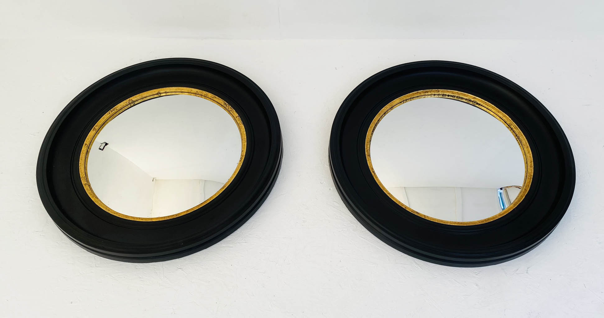 CONVEX WALL MIRRORS, a pair, 74cm diameter, Regency style with black and gold circular frames. (2)