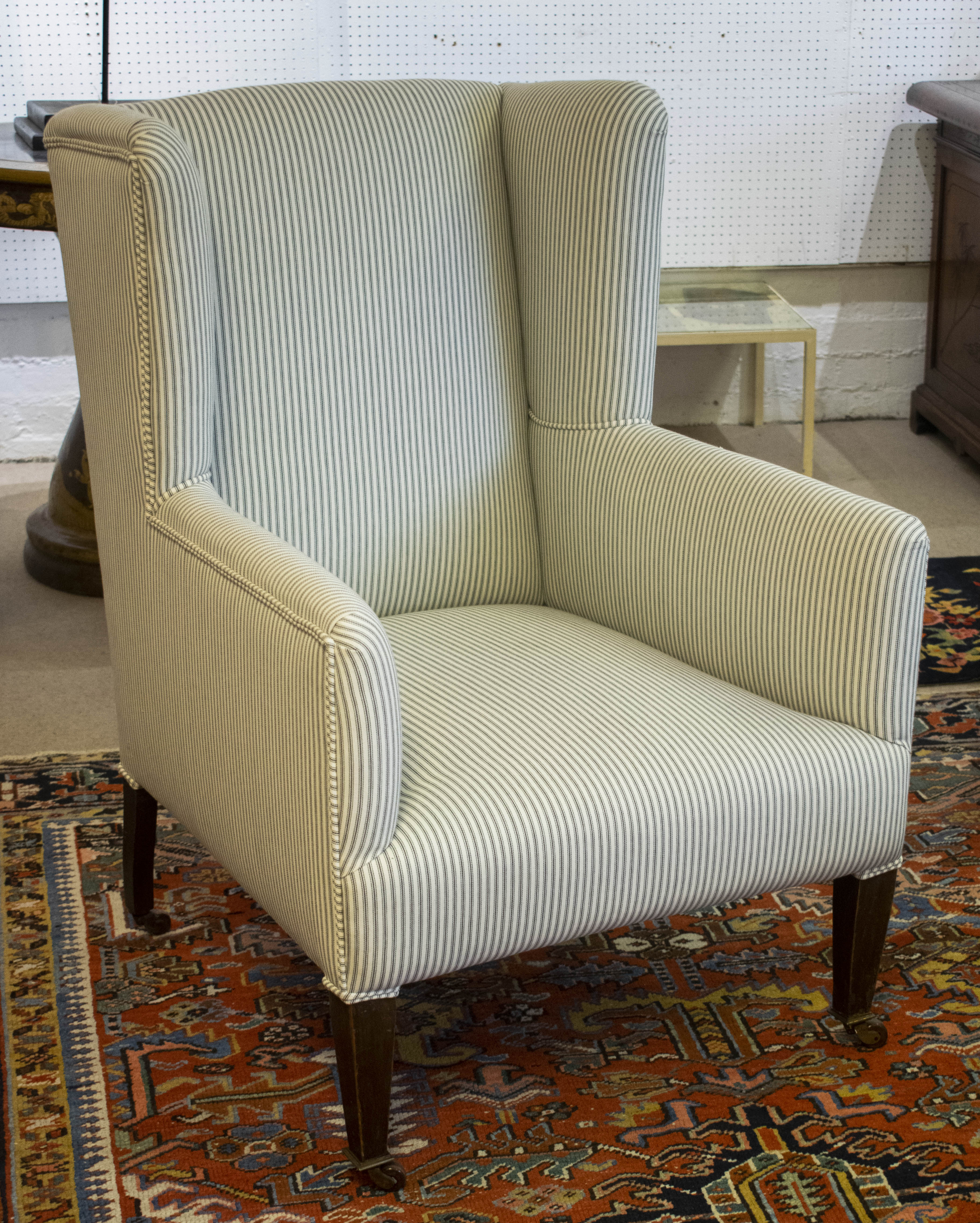 WING ARMCHAIR, 100cm H x 68cm W, Edwardian, newly upholstered in ticking on ceramic castors.