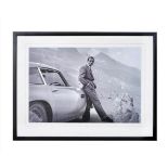 SEAN CONNERY AS JAMES BOND with his Aston Martin, framed and glazed, 63cm x 83cm.