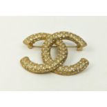 CHANEL BROOCH, in the form of the Chanel logo, gilt metal and set with diamontes, approx 5cm x 4cm.