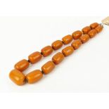 A BUTTERSCOTCH AMBER NECKLACE, fitted with seventeen oblong barrel shaped beads, silver clasp,