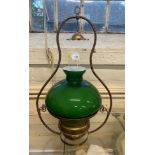 A brass oil lamp with a green glass overlay shade, 58cm high and a brass gong, 36cm high (2)