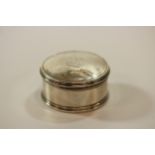 A Small Circular Silver Box. Apparently unmarked. The detachable cover engraved with a crest,