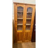 A Modern Pine Display Cabinet. The glazed doors enclosing three shelves. With interior lighting.