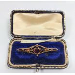 A 9ct gold bar brooch set with a red stone.