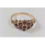 A ladies gold colour metal ring set with red stones, possibly rubies. Size O.