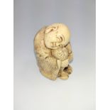 A late 19th century bone carving of a Japanese boy resting, his clothing heavily decorated in all