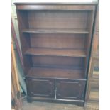 A Stained Wood open bookcase. 20th century. Of two shelves above a two door cupboard. Approx. 140