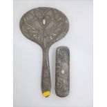 A ladies pewter Art Nouveau hand mirror and matching clothes brush. Each Decorated with a stylised