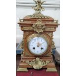 A highly ormolu decorated clock with white enamel dial and Arabic numerals. The finial is a winged