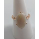 A gold metal ring set with a polished opal of oval form, size O.