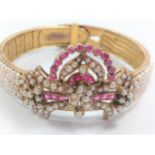 A gold colour metal bangle, set with a large amount of seed pearls and some red stones, possibly