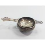 A silver plated tea strainer and bowl.