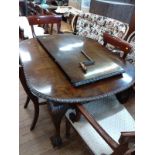 A dark mahogany dining table with one spare leaf and 8 chairs (2 of which are carvers). With winder.