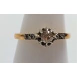 An 18ct gold ring set with a 10-point diamond and diamond set shoulders, size L.