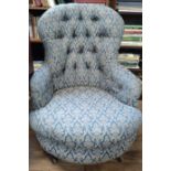 A low seated, button-back armchair with pale-blue patterned upholstery.