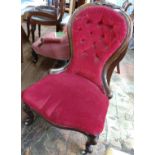 A Victorian button back nursing chair, upholstered in red and on casters.